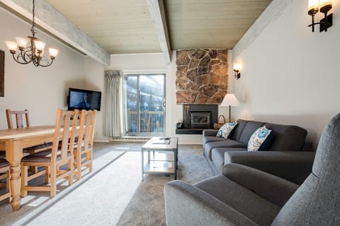 Unwind by the stone fireplace in your mountain retreat, where rustic beams and cozy seating create the perfect alpine escape.
