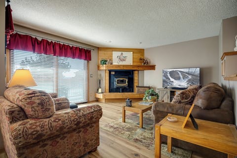 Settle into plush seating beside your crackling fireplace, where warm wood accents and mountain views create the perfect retreat.