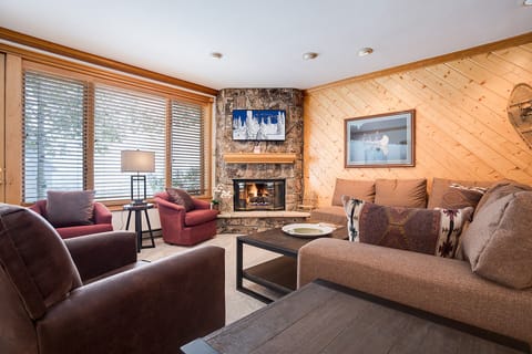 Cozy up by your stone fireplace with plush seating and warm wood accents creating the perfect mountain retreat atmosphere.