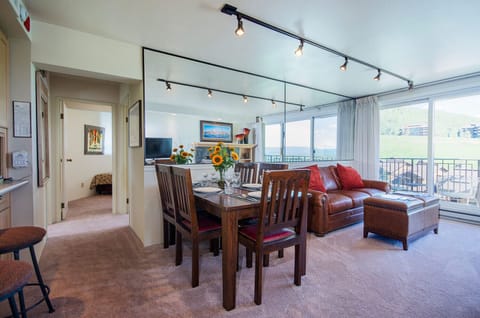 Relax in your open-concept living space where rich leather seating meets mountain views through expansive windows, perfect for memorable meals together.