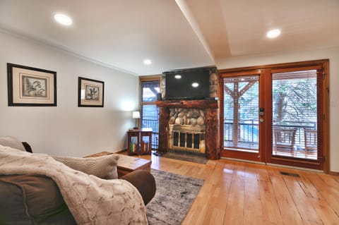 Open living area with hardwood floors, gas fireplace and mantle mounted TV
