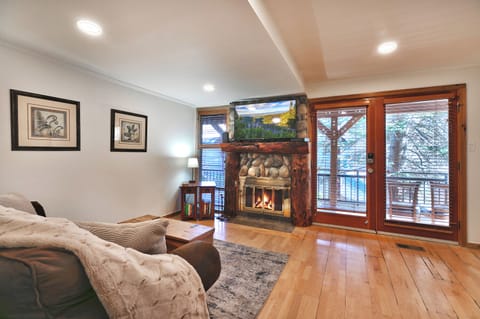 Open living area with hardwood floors, gas fireplace and mantle mounted TV
