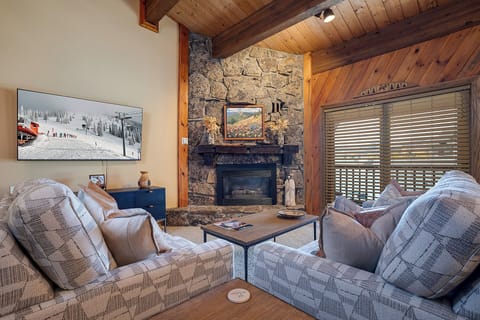 Sink into plush seating by your crackling stone fireplace, where exposed beams and ski slope views create the perfect mountain retreat ambiance.