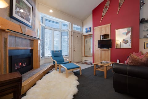 Curl up by your crackling fireplace in this cozy living room, where warm wood tones and a vibrant accent wall create the perfect retreat.