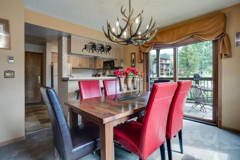 Gather around this rustic dining table under a striking antler chandelier, where your mountain getaway meals become memorable moments. The open kitchen and balcony access create the perfect flow for entertaining.