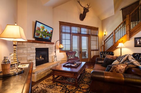Cozy up by the crackling fireplace in your rustic retreat, where leather seating and mountain charm create the perfect evening sanctuary.