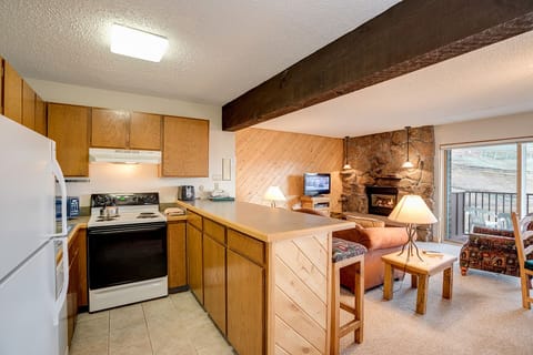 Your cozy mountain retreat features a fully equipped kitchen, warm living area with stone fireplace, and rustic charm throughout.