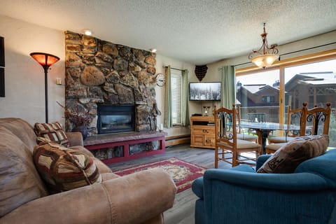 Unwind by your cozy stone fireplace in this mountain retreat's living room, where warm lighting and rustic charm create the perfect après-ski sanctuary.