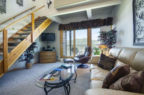 Unwind in your spacious loft-style living room with plush leather seating, mountain views, and rustic wood beams creating the perfect retreat.
