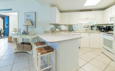 Gather around the kitchen bar with friends for casual meals, surrounded by bright cabinetry and inviting decor