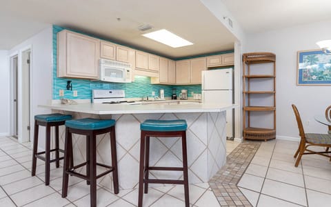 Enjoy cooking in this cheerful kitchen with turquoise accents, white appliances, and a convenient breakfast bar