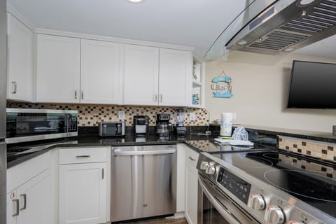 This kitchen features sleek stainless appliances, granite countertops, and a TV, perfect for cooking and entertaining