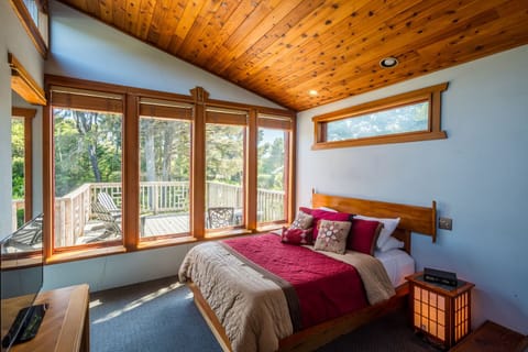 A serene primary bedroom with ocean peaks from the deck.