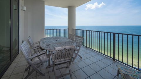 This inviting balcony features a round wooden table and chairs, perfect for enjoying stunning beachfront views