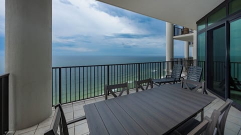 This spacious balcony features a large dining table and comfortable seating, perfect for enjoying beachfront views