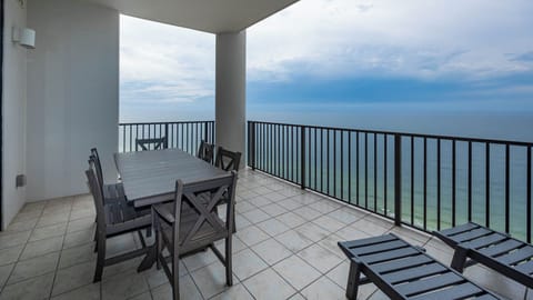 This outdoor balcony area features a large table and chairs, perfect for enjoying meals with a stunning beachfront view
