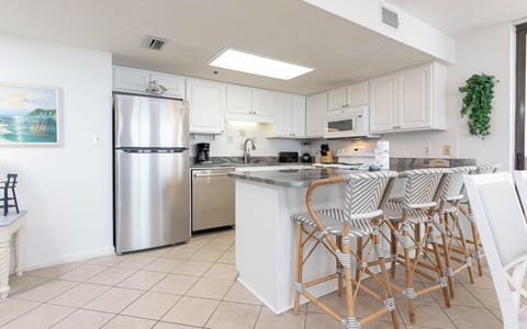 White cabinetry and a sleek breakfast bar complement the modern kitchen, featuring stylish bar stools for casual dining