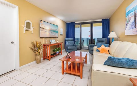 Cozy living area featuring a large TV, vibrant decor, queen sofa-sleeper, and a stunning balcony beach view