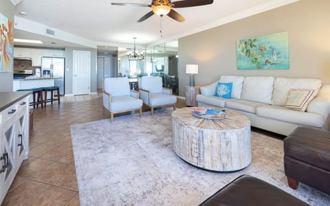 Unwind in the inviting living area with stylish seating, a round coffee table, and vibrant coastal decor