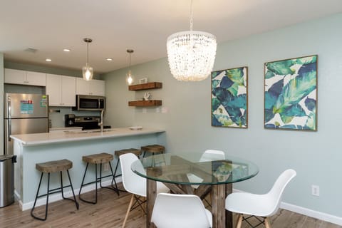 Your open kitchen flows seamlessly into an elegant dining space, where a stunning crystal chandelier illuminates meals shared around the glass table.