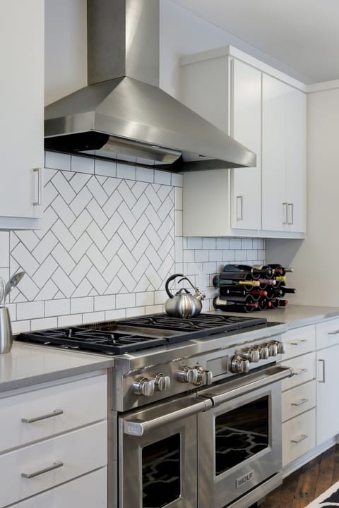 Cook your favorite meals on professional-grade appliances with elegant white cabinetry and herringbone tile backsplash surrounding you.
