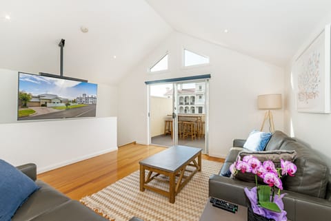 The large ceiling hung TV complements the airy feel to the living area