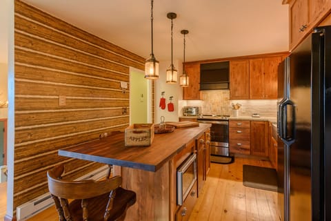 Center Island with Butcher Block Counter, Pendant Lighting, and Seating for 3