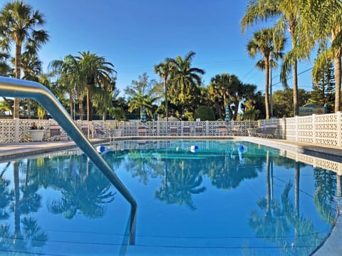 Community pool featuring a water slide, pool deck, and surrounding palm trees
