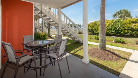 Enjoy a relaxing outdoor dining space with a glass table and chairs, surrounded by lush greenery and a peaceful atmosphere