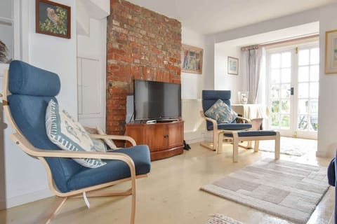 Bright living room at Mulberry Cottage featuring comfortable seating, Smart TV and sea-inspired décor for relaxed holiday evenings.
