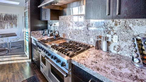 Dark modern kitchen w/ 6 burner gas stove, oversized wine cooler, & double ovens