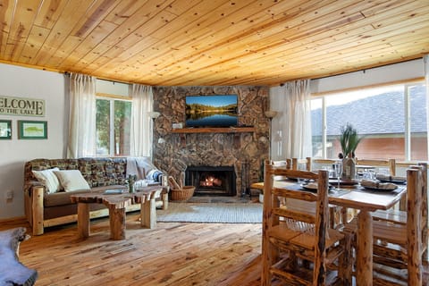 Open living area with stone fireplace, oak floors, pine ceiling, & log furniture