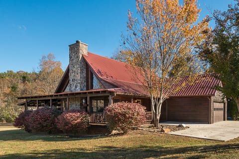Side and front view of log cabin with new wrap around porch and stone fireplace