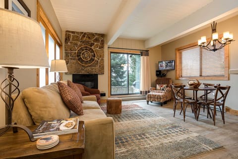 Unwind in your cozy mountain retreat with stone fireplace, comfortable seating, and dining space perfect for memorable evenings.