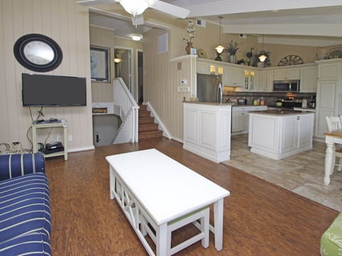 Kitchen with new cabinets, appliances, and stone flooring. Living area has wood.