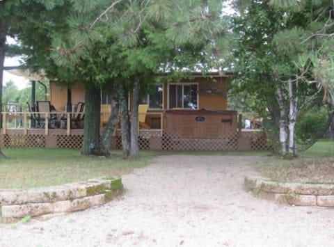 The deck off of the cabin with a hot tub, BBQ gas grill and a shaded eating area