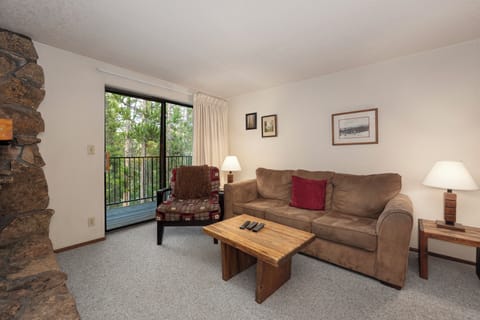 Relax in your cozy living room with plush seating and warm fireplace, while enjoying forest views from your private balcony.
