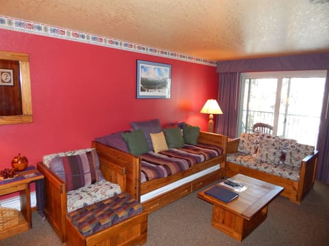 Unwind in your cozy living space with rustic wooden furniture, warm colors, and mountain views from your private balcony.