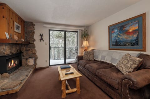 Cozy up in this warm living room where your stone fireplace crackles as you relax on the plush sofa, gazing at snowy trees through large windows.