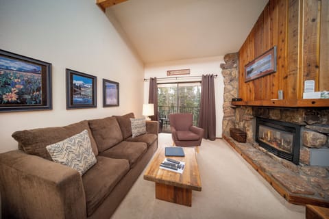 Cozy up on plush sofas before your rustic stone fireplace, where mountain views through large windows complete your perfect alpine retreat.