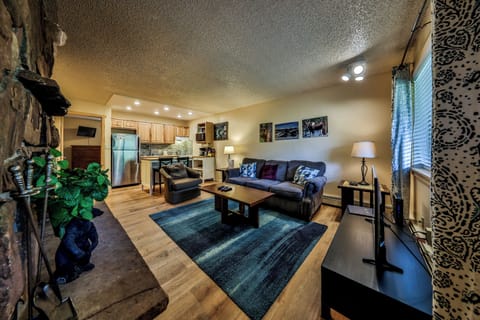 Relax in your spacious living area with exposed stone walls, modern kitchen, and cozy seating perfect for unwinding after adventure.