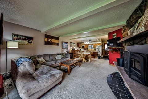 Relax in your spacious living area featuring plush seating, a warm fireplace, and open flow to the dining space and kitchen.