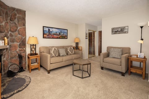 Relax in your cozy living room with plush seating, stone fireplace, and modern amenities for the perfect mountain getaway.