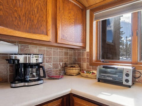 Your well-equipped kitchen corner features everything you need for morning coffee and quick meals, with warm wood cabinets and mountain views.
