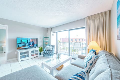 Living room with a large flat-screen TV and direct access to a private balcony.