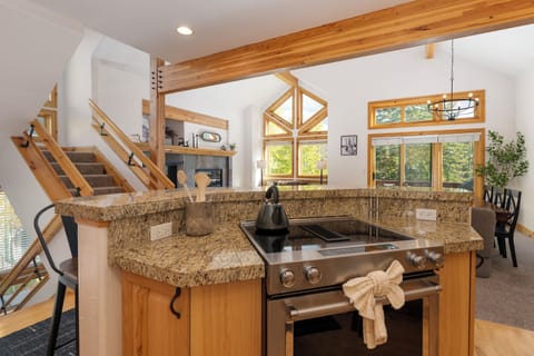 Cook with ease on the granite island while soaking in forest views through soaring windows in this bright, open kitchen.