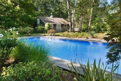 Heated pool surrounded by greenery and an original horse stable barn.