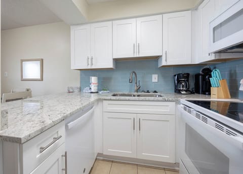 This kitchen features sleek white cabinetry, granite countertops, and modern appliances, perfect for preparing meals