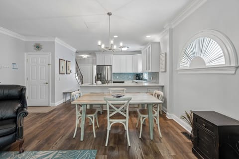 Picture yourself gathered around this coastal-inspired dining table, savoring meals in this bright, open-concept space. The soft teal hues and warm wood floors create a relaxed, beach-cottage vibe that feels like home.