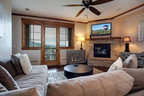 Sink into plush sofas by your stone fireplace while mountain views stretch beyond French doors. Perfect for cozy evenings with your favorite shows.